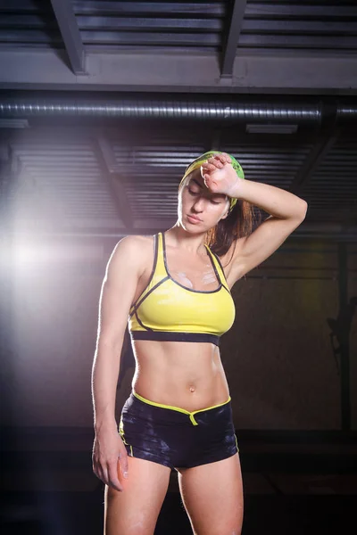 beautiful, strong, slender, in good physical shape in the gym doing exercises. Dressed in short shorts and tank top green, on the head bandage.