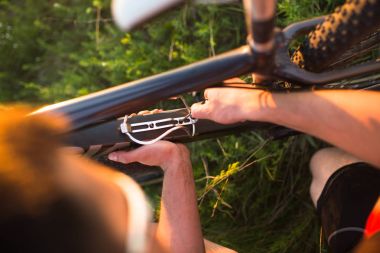 Adam şişe kafesi niteliğine bir alanda bir dağ bisikleti gün batımında ayarlar