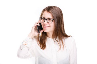 Bir cep telefonu üzerinde konuşurken beyaz izole arka plan üzerinde beyaz bir gömlek güzel genç kız. Gülümsüyor portre bel