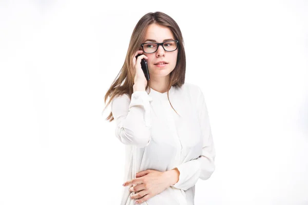 Hermosa joven con una camisa blanca sobre fondo blanco aislado hablando en un teléfono móvil. Retrato de sonrisas en la cintura —  Fotos de Stock