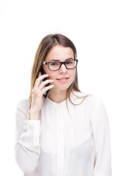 Menina bonita em uma camisa branca no fundo isolado branco falando em um telefone celular. Sorrisos retrato para a cintura — Fotografia de Stock
