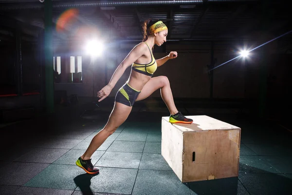 Mladá, silná svalová dívka skáče v tělocvičně k povýšení. Trénink nohou a kardio — Stock fotografie