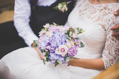 Gelin ve damat gelin buketi taşıyor.