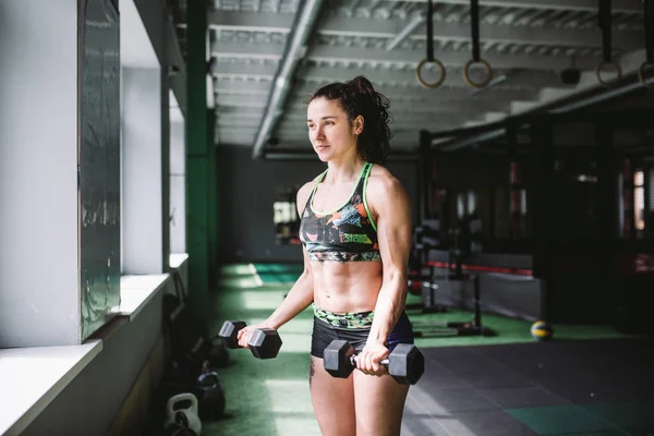 Atraktivní fit žena vyjde s činkami jako konceptuální v posilovně fitness — Stock fotografie
