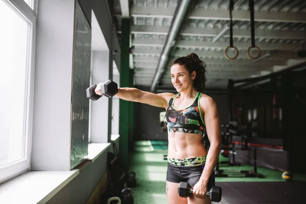 Çekici uygun kadın dumbbells ile bir fitness salonunda kavramsal olarak dışarı çalışır