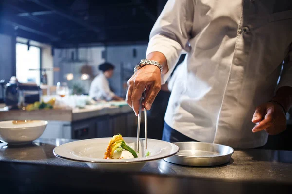 Food-Konzept. Zubereitung traditioneller italienischer Speisen. Koch in weißer Uniform dekoriert Fertiggericht im Inneren der modernen Restaurantküche. — Stockfoto