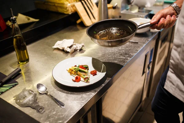 Food-Konzept. Zubereitung traditioneller italienischer Speisen. Koch in weißer Uniform dekoriert Fertiggericht im Inneren der modernen Restaurantküche. — Stockfoto