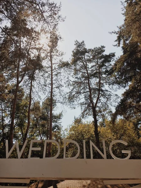 Свадебная надпись с большими белыми буквами на фоне зеленого парка . — стоковое фото