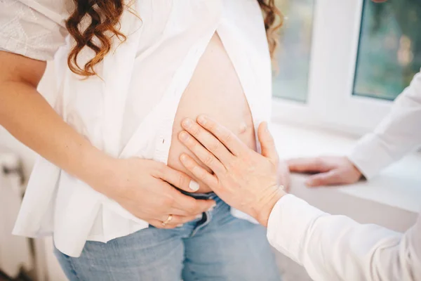 Wanita membuka perutnya yang sedang hamil dan pria meletakkan tangannya di atasnya — Stok Foto