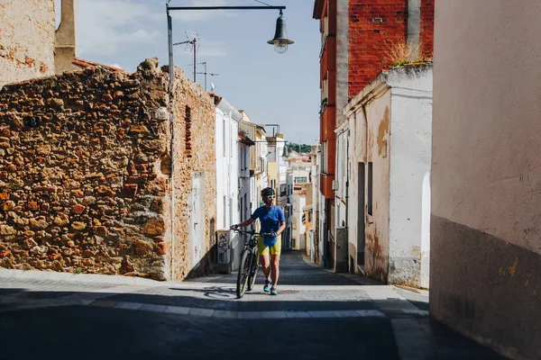 İspanya ve gülümseyen bir eski cadde boyunca bir dağ bisikleti ile kask ve bisiklet düzgün ve beyaz gözlüklü kız gider — Stok fotoğraf