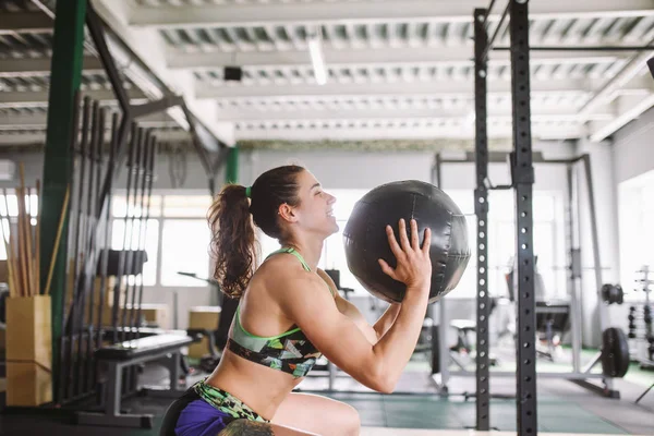 Friska flicka gör övningar på musklerna i ben och händer med bollen i gymmet — Stockfoto