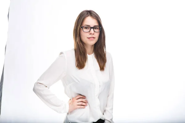 Hermosa joven en gafas con montura negra, con pelo castaño sobre hombros y camisa blanca sobre fondo blanco aislado . —  Fotos de Stock