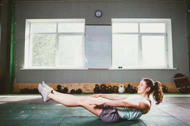 genç ve güçlü kız mide kaslarının basın için yerdeki spor egzersizleri yapıyor bir gülümseme ile