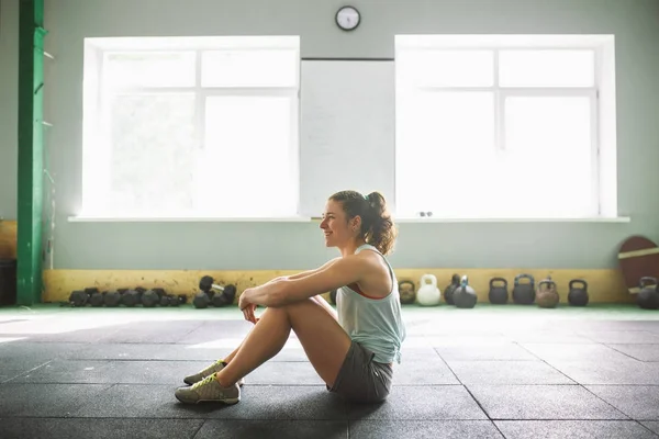 Chica joven y fuerte con una sonrisa haciendo ejercicios para los músculos del estómago, presione en el suelo en la espora — Foto de Stock