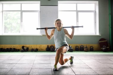 güzel genç kadın spor salonunda kalçalarda bir ağırlık sopayla sit-up egzersizleri yapıyor