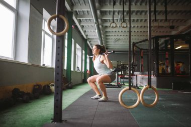 güzel genç kadın spor salonunda kalçalarda bir ağırlık sopayla sit-up egzersizleri yapıyor