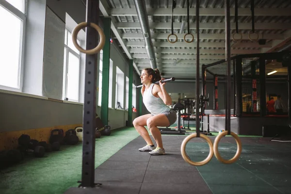 güzel genç kadın spor salonunda kalçalarda bir ağırlık sopayla sit-up egzersizleri yapıyor