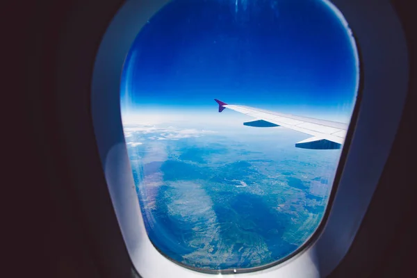 Op zoek via venster vliegtuig tijdens de vlucht in vleugel blauwe hemel — Stockfoto