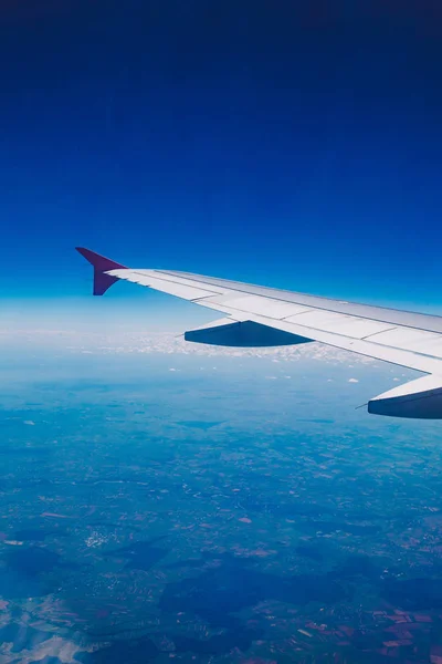 Mirando a través de aviones ventana durante el vuelo en el cielo azul del ala — Foto de stock gratuita