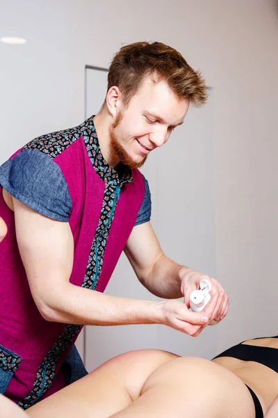 Un terapeuta masculino joven está aplicando aceite a la piel de la niña al paciente para modelar masajes y pruebas musculares kinesiológicas f para el hermoso efecto corporal — Foto de Stock