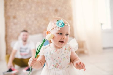 küçük bebek kız sarışın ailesi arka plan üzerinde evin içinde bir renk tulbpin tutarak başını bir bandaj ile.