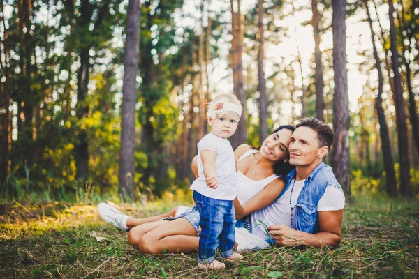 A háttérben a szülők feküdt a füvön, tanulás séta a park természet pihenő egyéves kislány. A gyermek első lépései — Stock Fotó