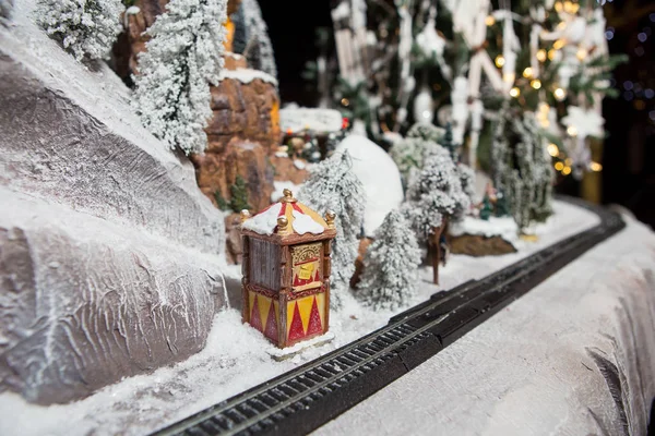 Weihnachtsdekoration große Gips-Deko Kindereisenbahn im Winter verschneite Schienen in den Bergen am Waldhang und ein Bahnhof mit Ticketverkauf — Stockfoto