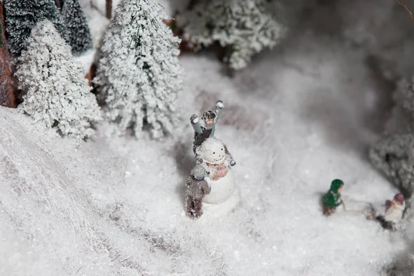 Παιχνίδι μεγάλη διακόσμηση Χριστούγεννα διακόσμηση. Οι άνθρωποι κάνουν έναν χιονάνθρωπο στο ανοιχτό χώρο κοντά στο δάσος — Φωτογραφία Αρχείου