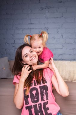 Sarışın kızı onun omuzları üzerinde ince bir genç güzel annesiyle oynamak, zevk ve sofa ahşap zemin üzerinde yakın takım şımartın