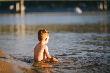 Erkek bebek sırtı ile bel nehir Reservoir oturur ve ufuk ötesine görünüyor. Yaz plaj tatil kavramı
