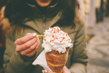 trdelnik veya Trdlo bir güzel kış kız Çek Cumhuriyeti, Prag Zirvesi'nde Noel pazarı elinde krema ile