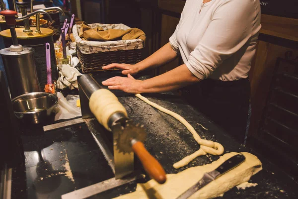 The hands of a female baker cook trdelnik or Trdlo national treat in the Czech Republic in winter — Stock Photo, Image