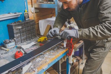 Bir kayak hizmet atölye bir erkek işçi kayaklar sürgülü yüzeyini onarır. Balmumu, kaldırma yeni balmumu kaldırmak için plastik bir kavgacı tip yardım close-up. Tema Kayak kaldırıma onarım