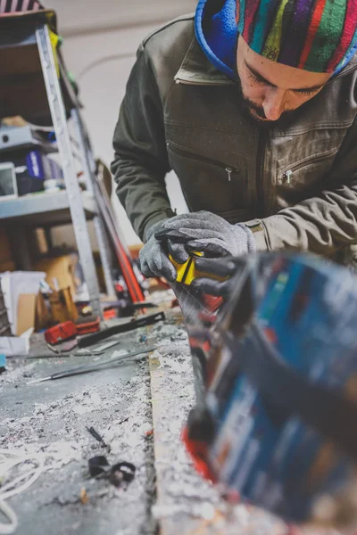 Male worker repairing Stone, edge sharpening in ski service workshop, sliding surface of the skis. sharpening of an edging of a mountain skis by means of the individual tool. Theme repair of ski curb