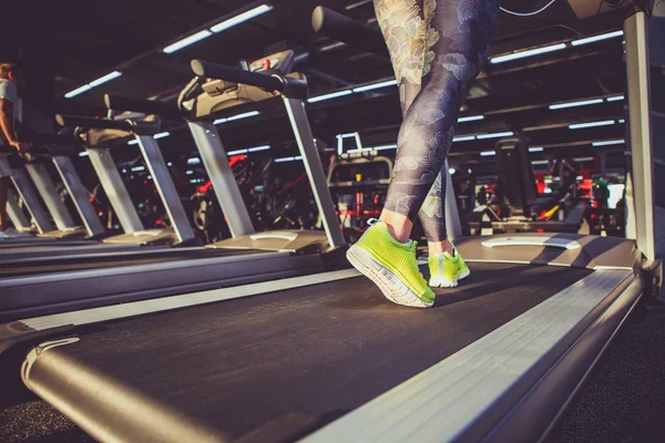 运动和减肥的主题。在一个模拟器上, 在健身房里跑步时, 一个年轻强壮的女子在一只浅绿色运动鞋的脚上关闭。训练前预热, 心肺训练 — 图库照片