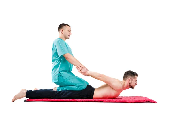 Joven macho recibiendo masaje por terapeuta en posición tailandesa tradicional sobre fondo blanco aislado — Foto de Stock