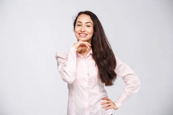 Retrato de una joven con una encantadora sonrisa dentada, pelo negro y ojos marrones sobre un fondo blanco en una camisa rosa. Emociones positivas y alegres —  Fotos de Stock