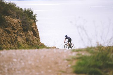 Tema turizm ve dağ bisikleti bisiklet. rocky, dağ yolu zemin Akdeniz kıyısında kosta brava kask ve bisiklet şortu giymiş İspanya yüksek hızda sürme genç adam
