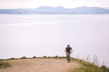 Tema turizm ve dağ bisikleti bisiklet. adam Akdeniz'de İspanya kosta brava kask ve spor giyim kıyısında arka planı rocky, kayalık yol yokuş yukarı sürmek