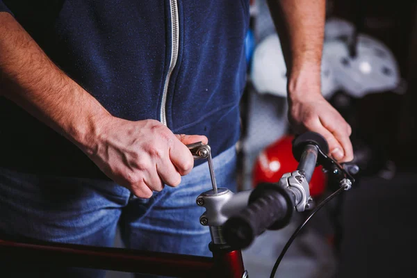 Thema Reparaturfahrräder. Nahaufnahme der Hand eines kaukasischen Mannes mit einem Sechskantschlüssel, um Vorbauten an einem Fahrrad zu installieren — Stockfoto