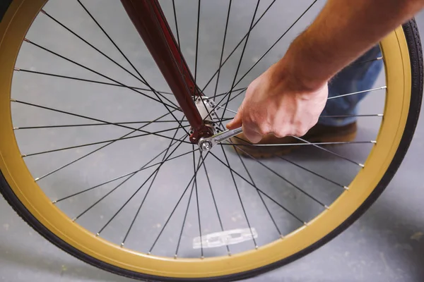 Тематические ремонтные велосипеды. Крупный план руки белого человека с помощью ручного инструмента Bike Tools Hub Cone Wrenc для настройки и установки Quick Releases и Thru Axles на красный велосипед — стоковое фото