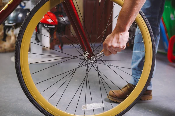 Theme repair bikes. Close-up of a Caucasian man's hand use a hand tool Bike Tools Hub Cone Wrenc to adjust and install Quick Releases and Thru Axles on a red bicycle — Stock Photo, Image