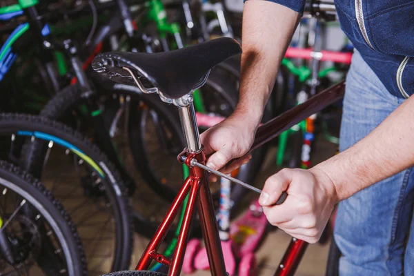 Theme repair bikes. Close-up of a Caucasian man's hand use a hand tool Hex keys to adjust and install the silver color Seat Posts on a red bicycle — Stock Photo, Image