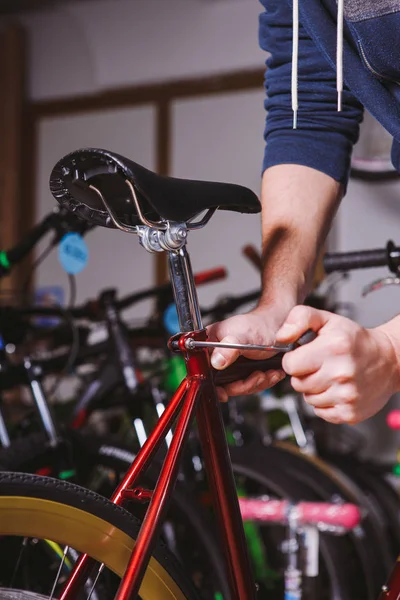 Tema reparera cyklar. Närbild av en kaukasisk mans hand Använd en hand verktyg Hex för att justera och installera silverfärg Seat inlägg på en röd cykel — Stockfoto