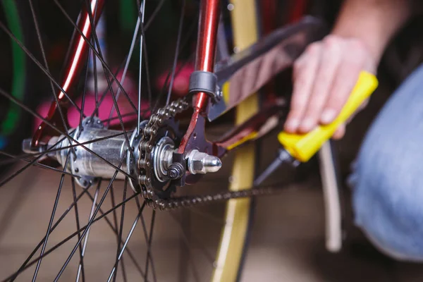 Sepeda perbaikan tema. Close-up of a Caucasian man 's hand use a Chain Lubricant in a yellow lubricator for llubricator a bicycle chain on a red bicycle — Stok Foto