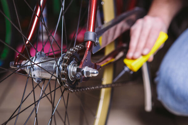 Theme repair bikes. Close-up of a Caucasian man's hand use a Chain Lubricant in a yellow lubricator for llubricator a bicycle chain on a red bicycle