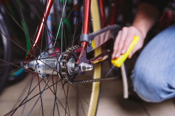 Sepeda perbaikan tema. Close-up of a Caucasian man 's hand use a Chain Lubricant in a yellow lubricator for llubricator a bicycle chain on a red bicycle — Stok Foto