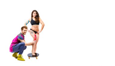 Tema Kinesiyoloji teyp Rehabilitasyon ve sporcu sağlığı. Güzel kız beyaz bir arka plan üzerinde duruyor, erkek terapist doktor kas ve tendon diz üzerinde stabilize etmek için renkli bir kaset tutkallar