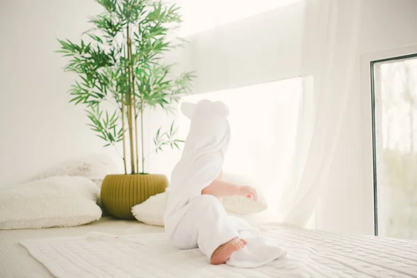 Красивий усміхнений новонароджений хлопчик вкритий білим бамбуковим рушником з веселими вухами. Сидячи на білому в'язанні, вовняні плед яскравий інтер'єр. Світло з вікна — стокове фото