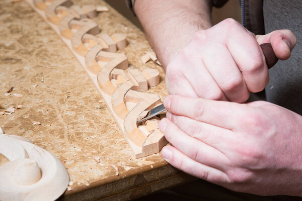 woodcarver creates a furniture ornament. Woodcarver's hands, chisels, tools, wood-carved ornament.